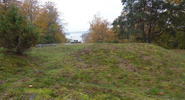 En disig och fuktig höstdag. Gravkullarna syns i förgrunden och bakom gravkullarna
är utsikten vida ut mot sjön Åsnen.
