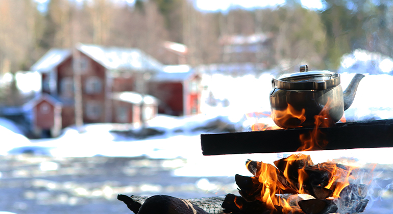 Kaffepanna över öppen eld i vinterlandskap.