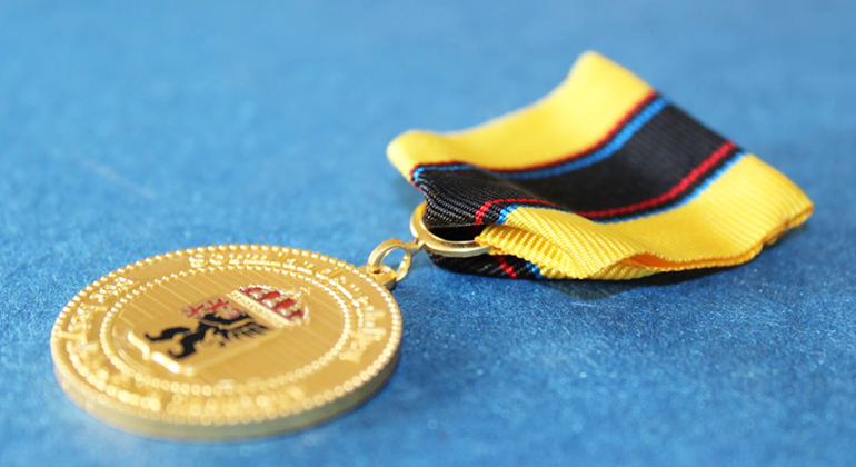 Bild på guldmedalj med blågult tygband