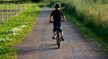 Ett barn som cyklar på en grusväg.
