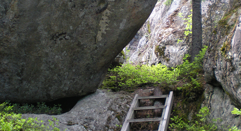 En stege/trappa i trä mellan stora stenar.