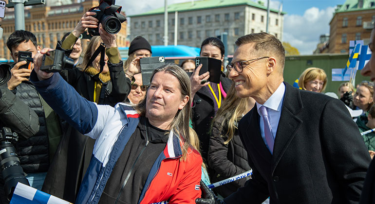 En man tar en selfie med Finlands president. I bakgrunden fotografer och stadsmiljö från Göteborg. 