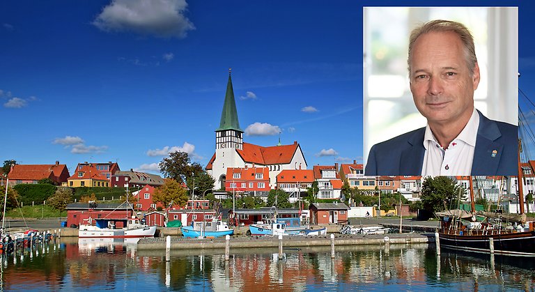 Bilden visar en vy över en hamn på ön Bornholm. Uppe i bildens högra hörn finns en porträttbild på Gotlands landshövding Anders Flanking.
