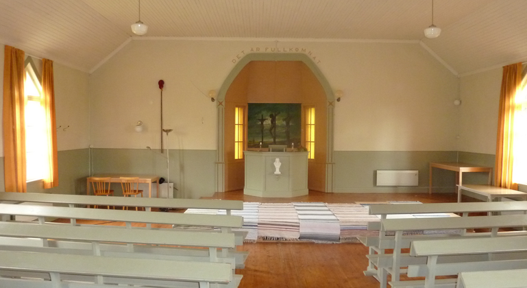 Samlingssalen i bönhuset, med träbänkar framför predikstolen som är placerad på ett upphöjt podium.