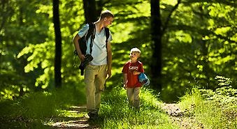 en vuxen man bärandes på en kamera och ett barn i skogen
