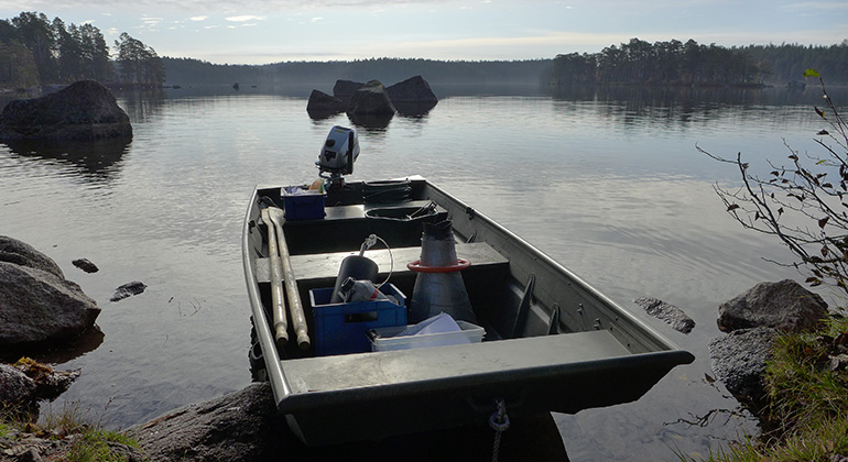 båt packad med provtagningsutrustning ligger i strandkanten av en sjö