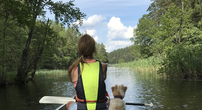 Kvinna och hund i kanot. Foto.