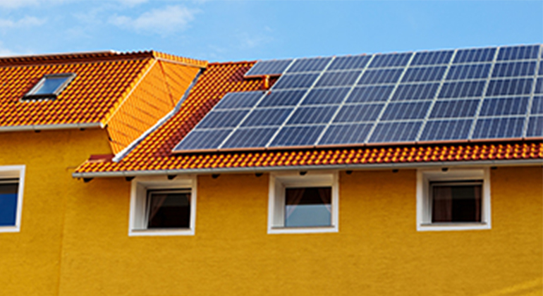 Gult hus med solpaneler på taket. 