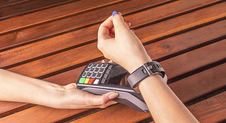 Betalning med en digital klocka vid betalningsterminal. Foto. 