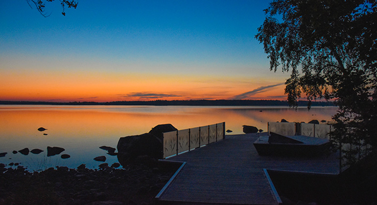 Brygga vid sjön Åsnen med en orange solnedgång i horisonten.