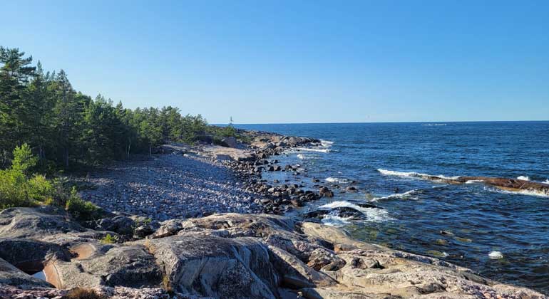 Klipphällar och en stenig strand sluttar ner i havet som är öppet ända till horisonten. Arsläjans naturreservat i Stockholms län. Foto: Länsstyrelsen