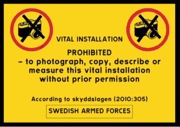 Skylt med texten Vital installation prohibited - to photograph, copy, describe or measure this vital installation without prior permission. According to skyddslagen (2010:305). Swedish armed forces.