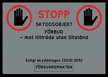 Stoppskylt med texten Stopp. Skyddsobjekt förbud - mot tillträde utan tillstånd. Enligt skyddslagen (2010:305). Försvarsmakten.