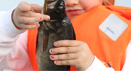 Fisk som hålls i av barn med orange flytväst.