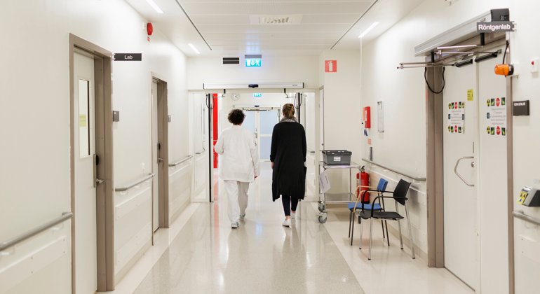 Två personer som går i en sjukhuskorridor.