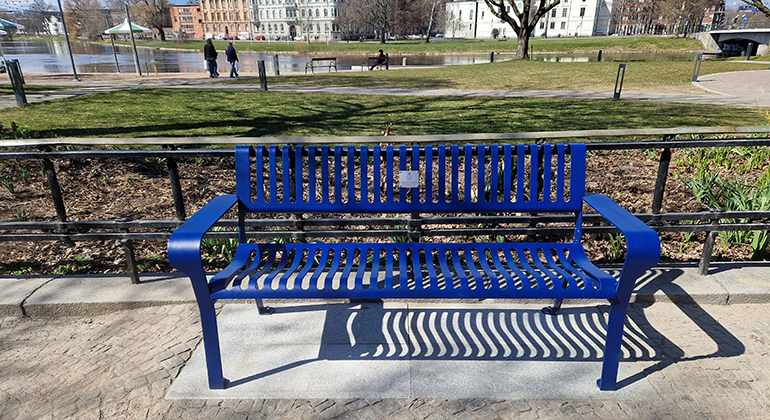 En blå bänk i metall i Residensparken.