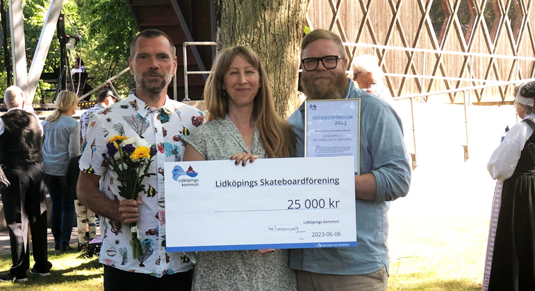Tre leende personer på bild, två män och en kvinna, håller upp en skylt där det står Linköpings skateboardförening 25000 kronor. 