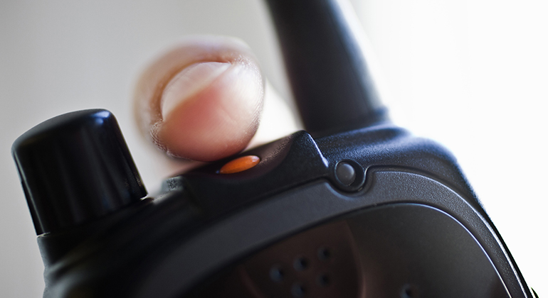 Ett finger trycker på larmknappen på en Rakelapparat