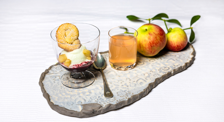 underlägg i keramik, glas med sorbét, två äpplen, dricksglas med innehåll