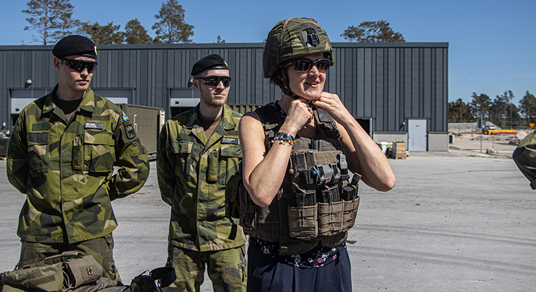 En person i solglasögon provar Försvarsmaktens stridshjälm och stridsväst.