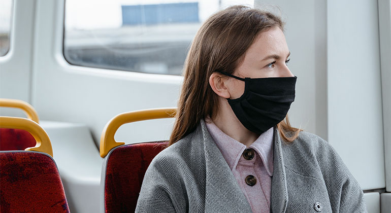 Flicka med munskydd som åker buss