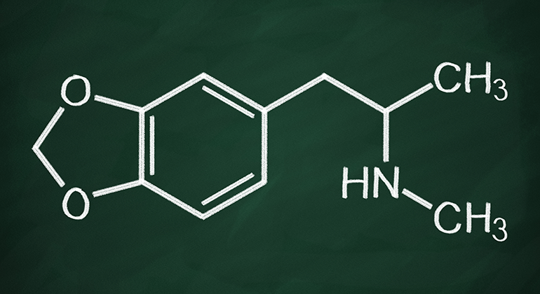 Mörk bakgrund och vita kritstreck som bildar den kemiska formeln eller strukturen för MDMA-molekylen.