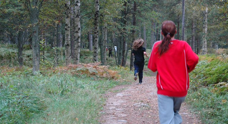 Ungdomar som joggar i en skog