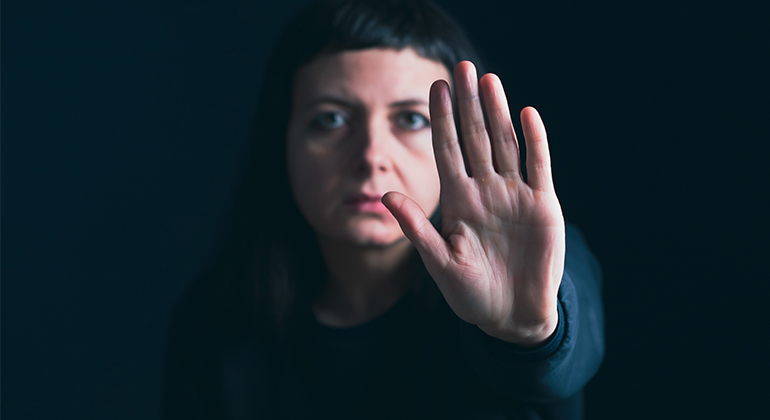 Kvinna säger stopp mot våld – visar med handen 