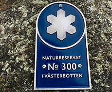 En blå skylt med texten "Naturreservat no 300 i Västerbotten".