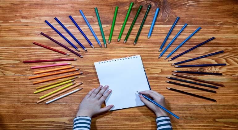 barnhänder på papper i cirkel av färgpennor
