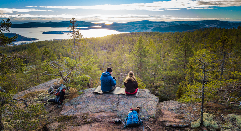 Foto av två personer som sitter på en klippa och tittar på en utsikt. 