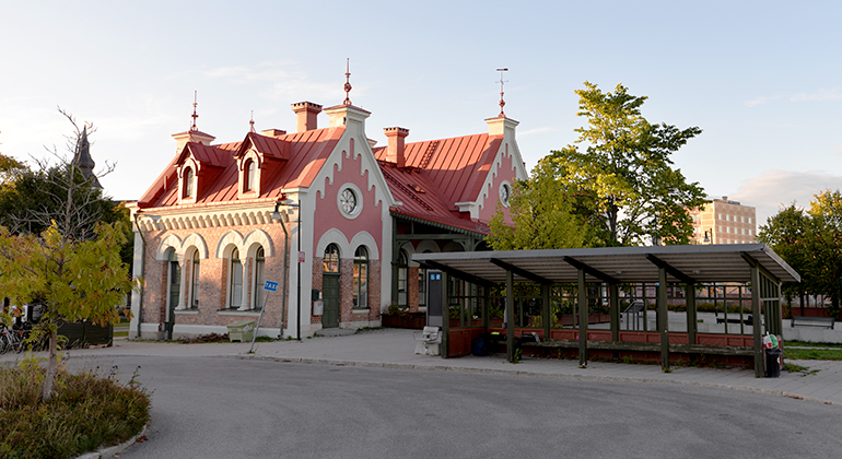 Solen lyser över det röd-rosa stationstaket på Hudiksvalls station