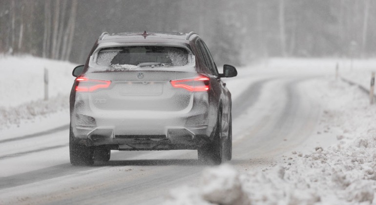 En snöig bil kör på vinterväglag. Foto: Martin Fransson