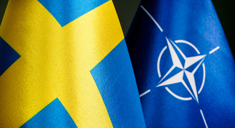 En del av den svenska flaggan till vänster och en del av Natos flagga till höger mot en svart bakgrund.