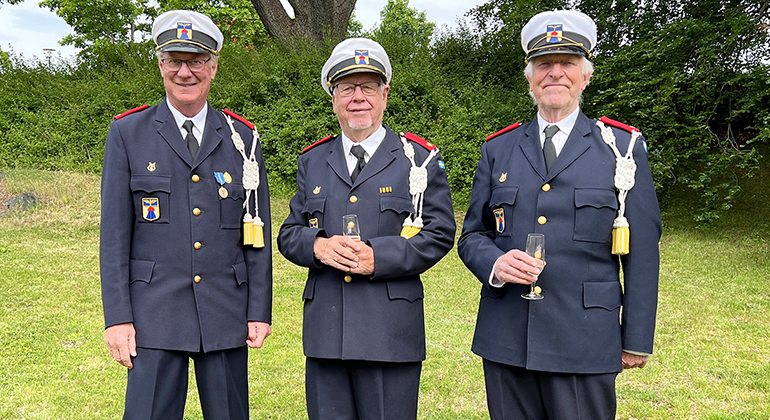 Tre män står i uniform tillsammans i Residenset trädgård, de tillhör Flygvapenfrivilligas musikkår.