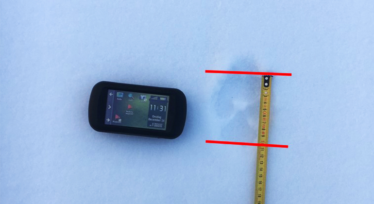 Spårstämpel i snö som mäts med ett måttband.