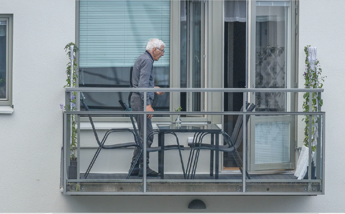äldre man står ensam i profil på en balkong