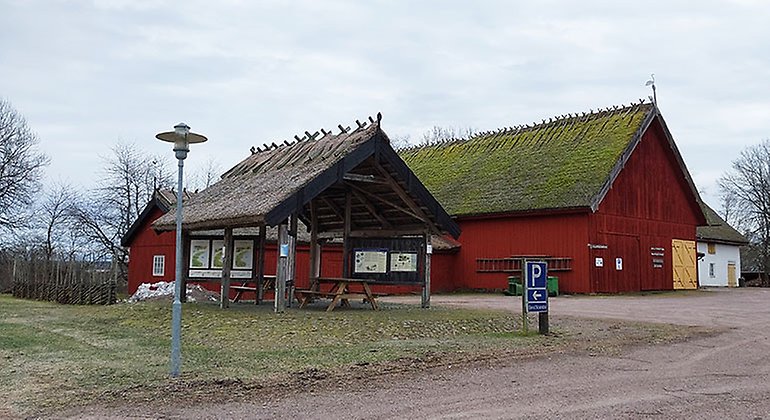 Två träbyggnader samt en grusväg och grusplan.