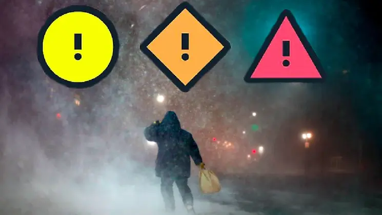 Bild på man i kraftigt regn med tre ett gult, orange och rött varningstecken på. 