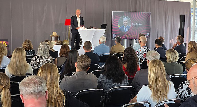 En man i kostym står på ett podium och talar inför en sittande publik vid invigningen av Frihamnsdagarna.
