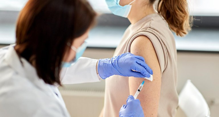 Bild på kvinna som får en vaccinspruta i armen.