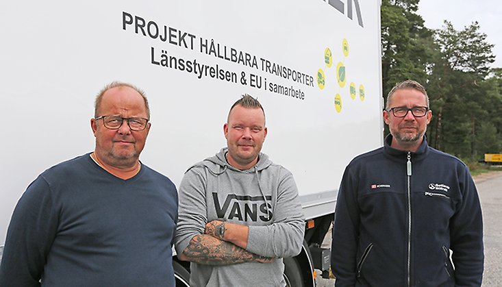 Bild på tre män framför en lastbil. 