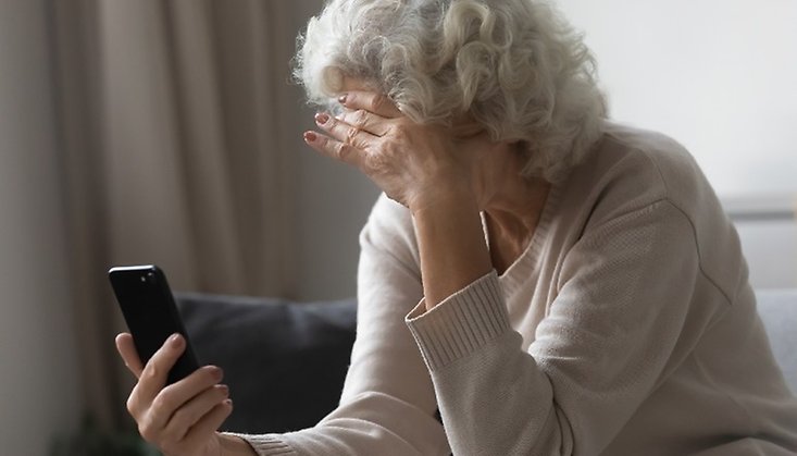 Äldre kvinna med mobiltelefon i handen.