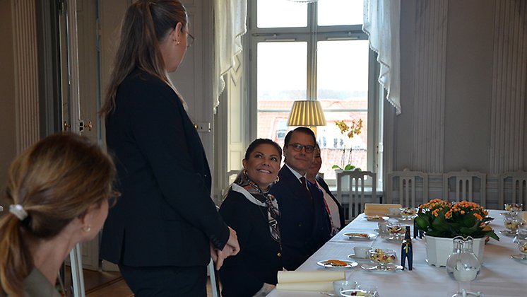 T.f. landshövding Camilla Fagerberg Littorin står upp och pratar mot kronprinsessparet som ler emot henne. 