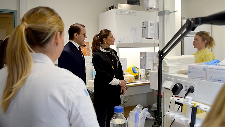 Kronprinsessan Victoria och Prins Daniel pratar med personal i ett laboratorium.
