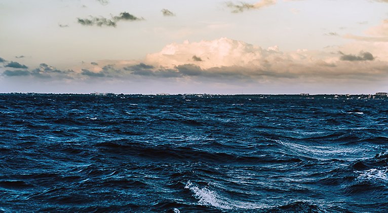 Skummande vita vågor på ett blågrått hav