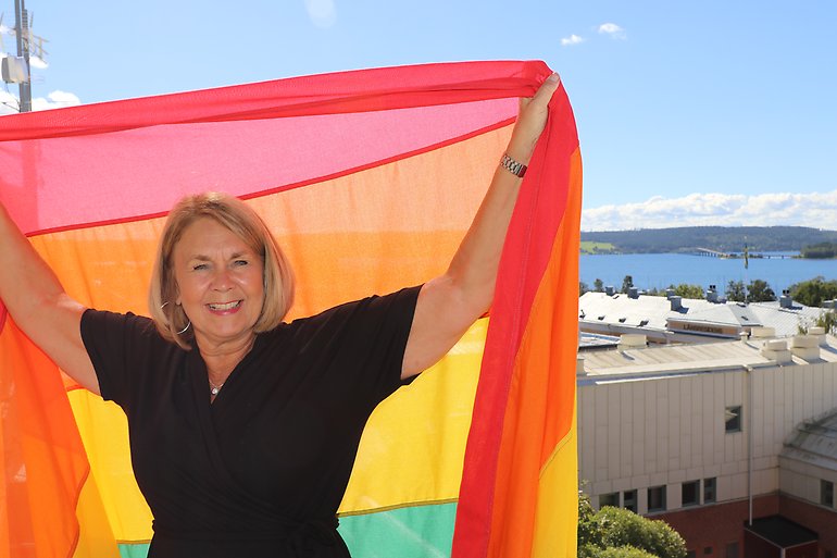Marita Ljung håller Pride-flaggan på Länsstyrelsens tak.