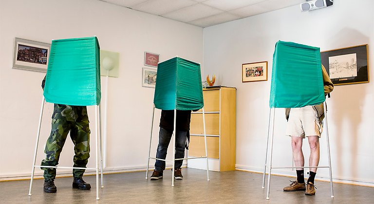 Röstande medborgare i vallokal.