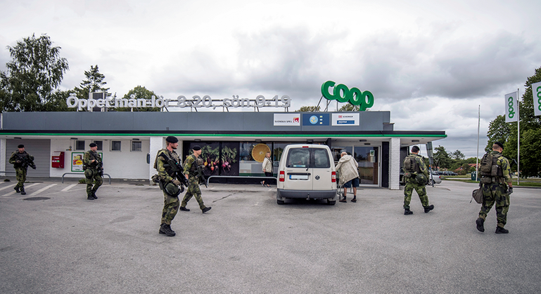 En handfull svenska soldater passerar till fots utanför en coop-butik i Sverige. 