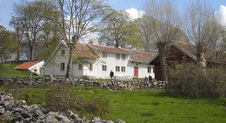 Fotografi över Mårtagården, vitt boningshus och en grön äng.